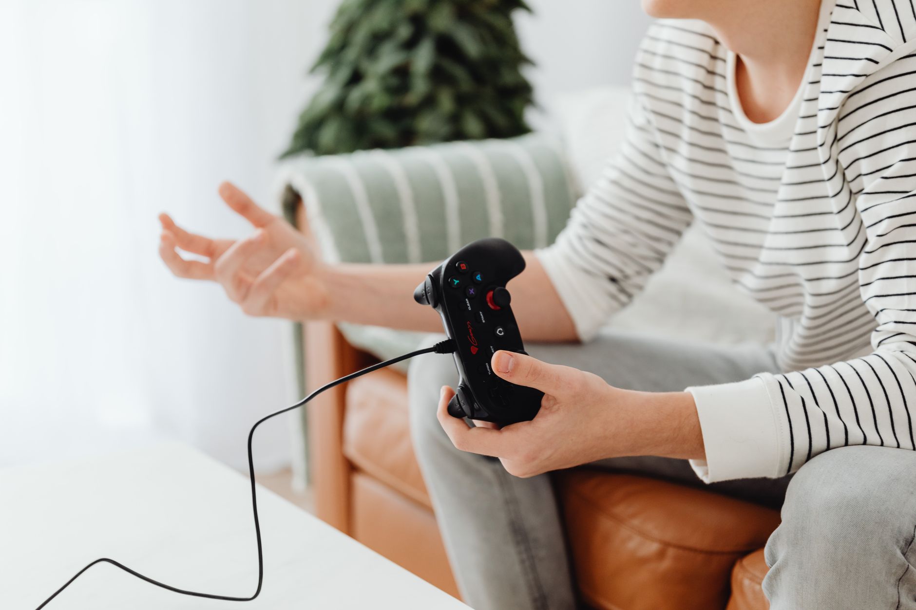 Close-up of a person playing video games at home with a wired controller on a couch. — "The Best Toto Sites for Reliable Onli